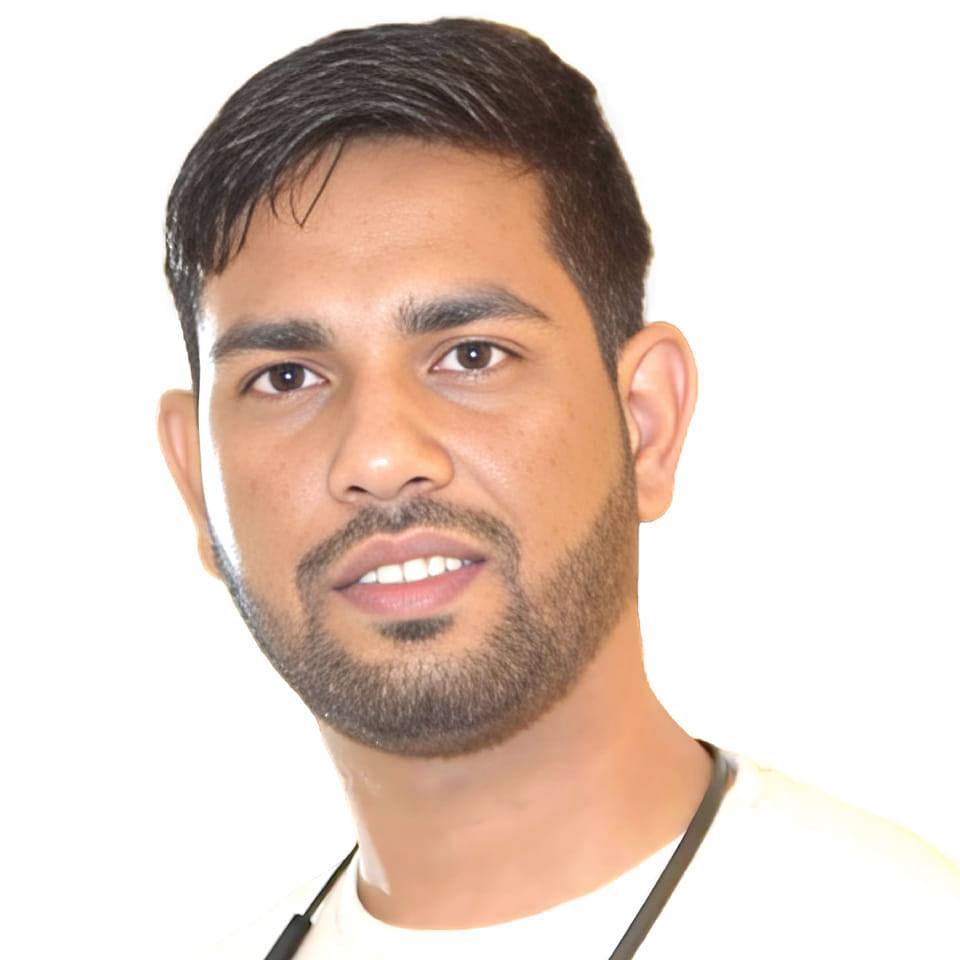 Aditya Raj Singh with short dark hair and a beard, wearing a white shirt and dark suit jacket, poses against a plain dark background.